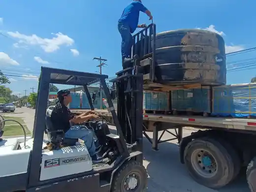 Forklift loading a water tank onto a trailer